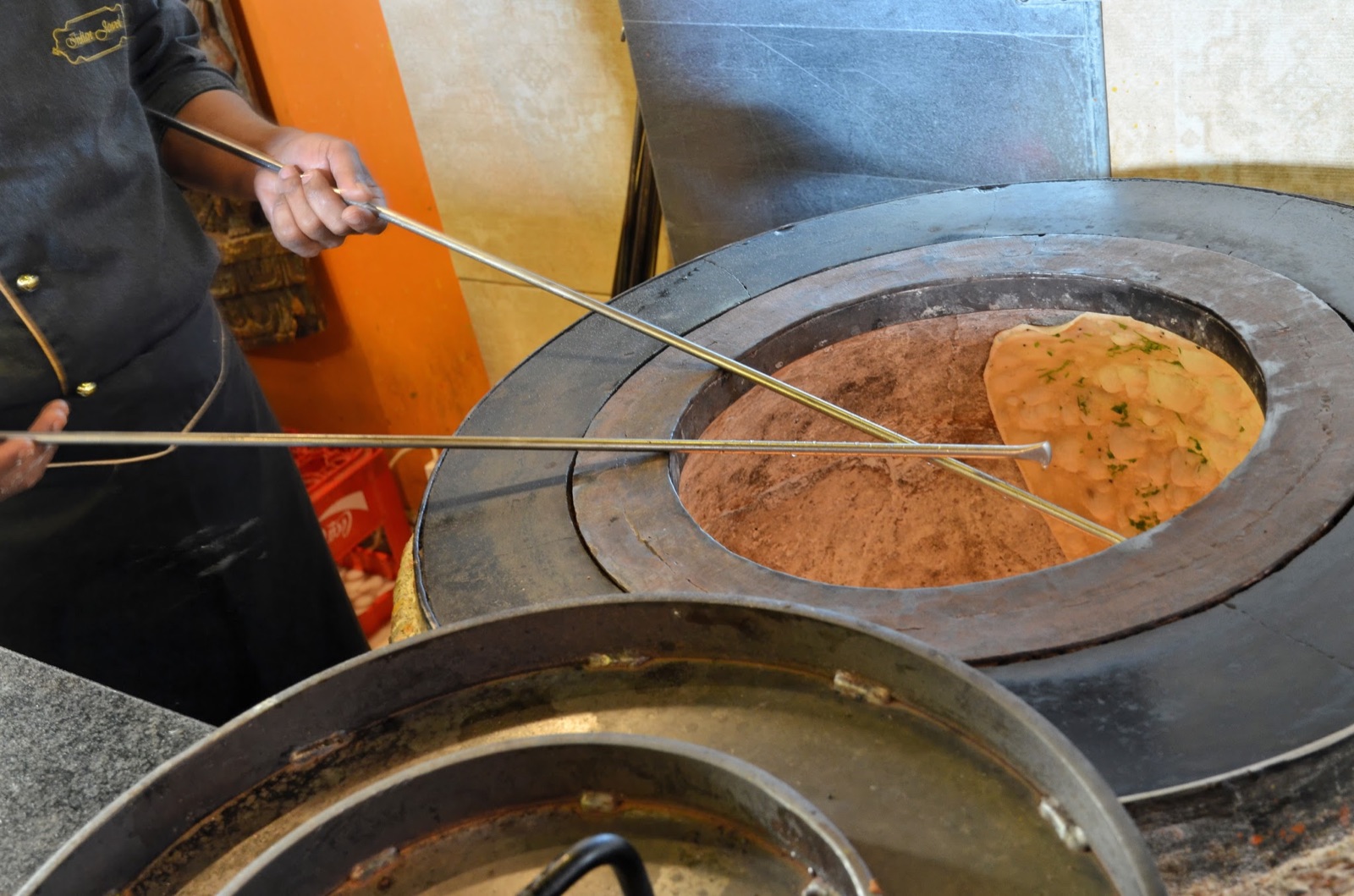 A chef baking fresh naan in the Indian Jewel tandoor
